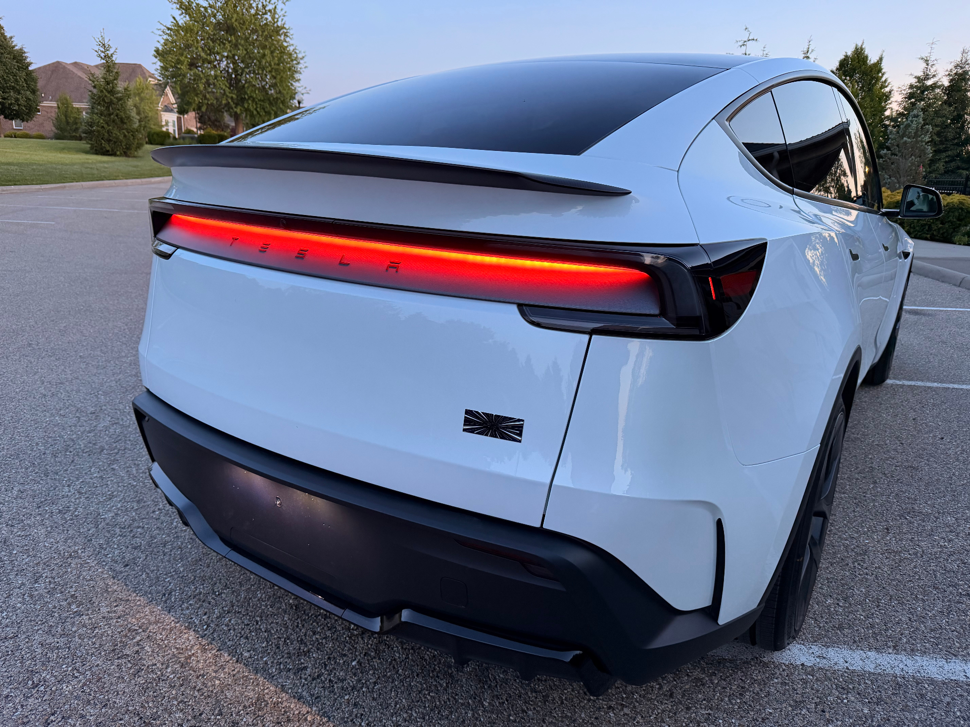 Rear view of a white Tesla Model Y Performance showing its full-width rear lightbar at dusk