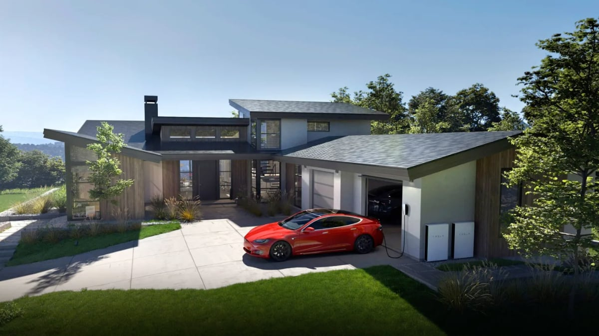 Modern home with Tesla solar roof, red Model S charging, and Powerwall units in the driveway