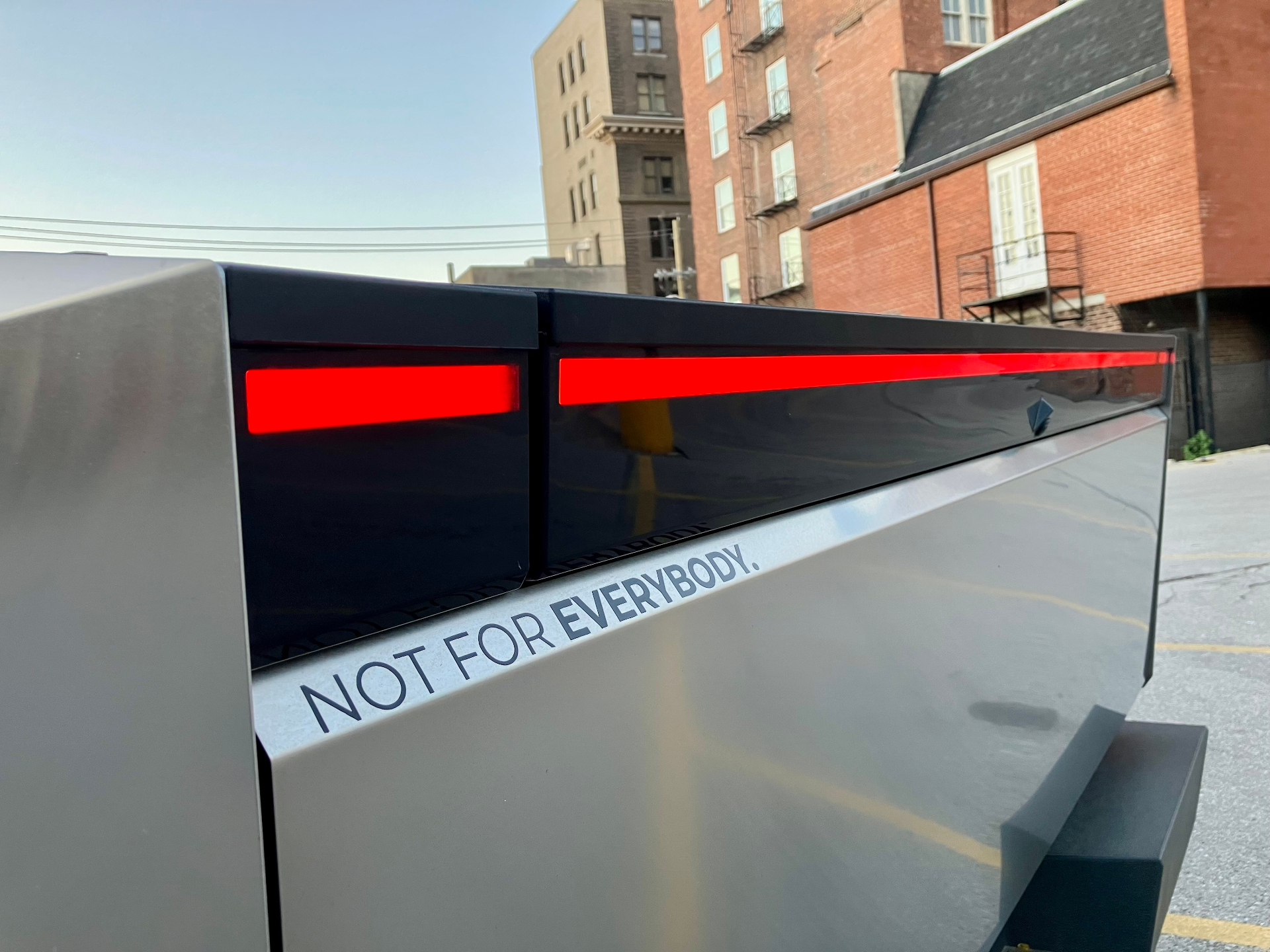 Tesla Cybertruck tailgate close-up with red light bar and Not For Everybody decal