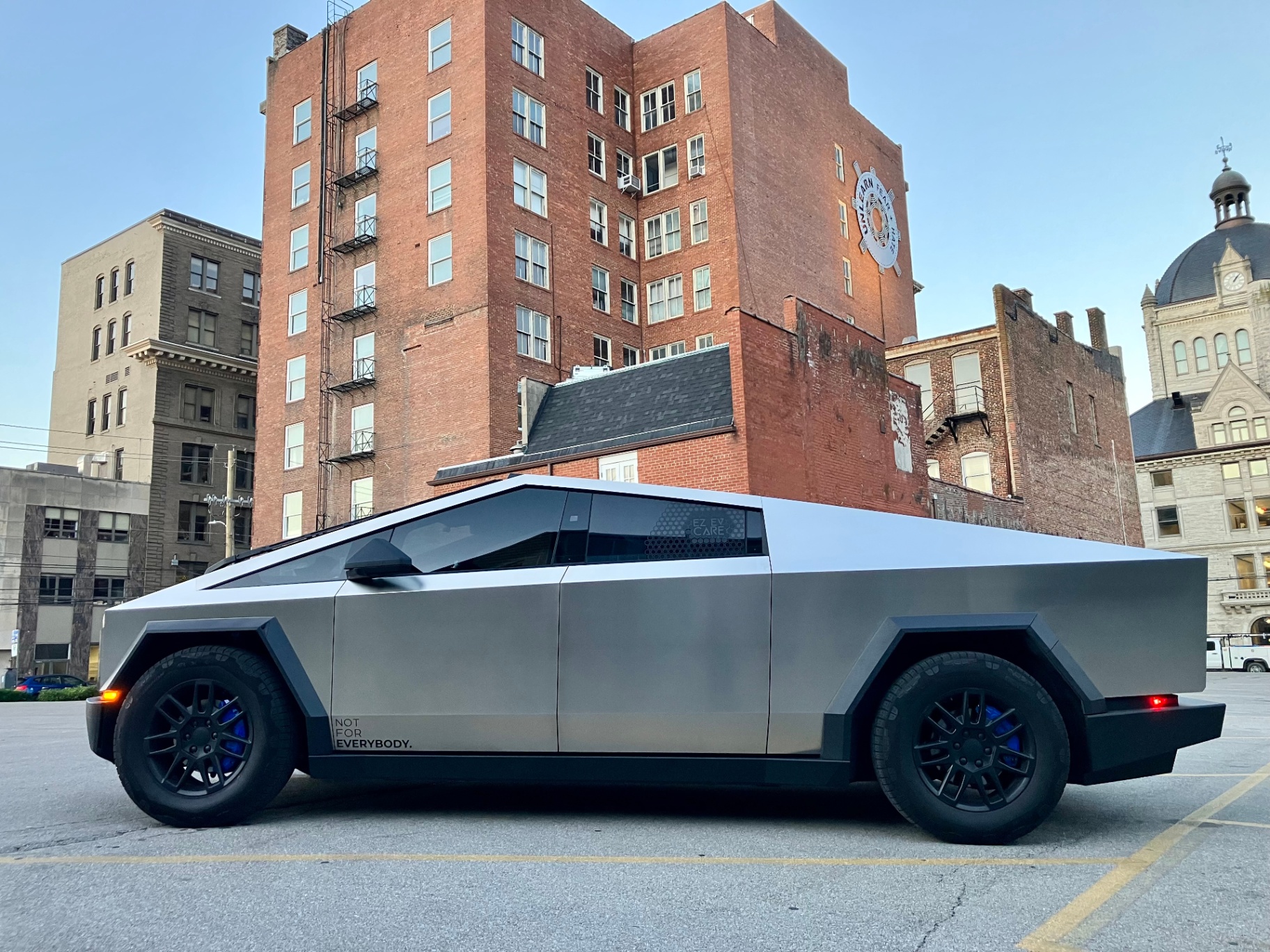 Tesla Cybertruck side profile parked downtown with brick buildings in background